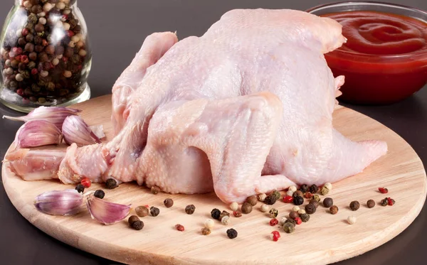 raw chicken carcass with peppercorns on a dark background