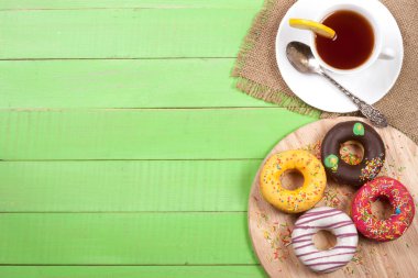 kopya alanı metniniz için yeşil bir ahşap zemin üzerine çay ile sırlı çörek. Üstten Görünüm