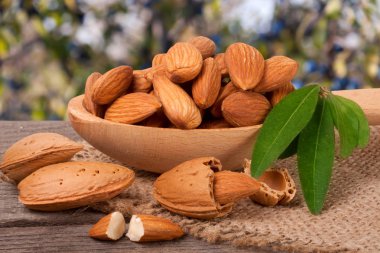 soyulmuş badem ile bir tahta kaşık masada yaprak yığını Bahçe arka plan bulanık