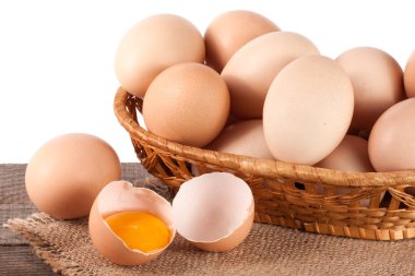 Beyaz bir arka plan üzerinde ahşap bir gemide bir hasır sepet yumurta