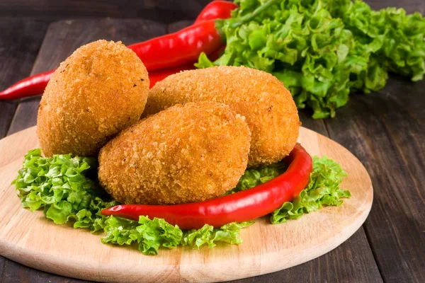 Tres chuletas empanadas fritas con lechuga en una tabla de cortar y fondo de madera —  Fotos de Stock