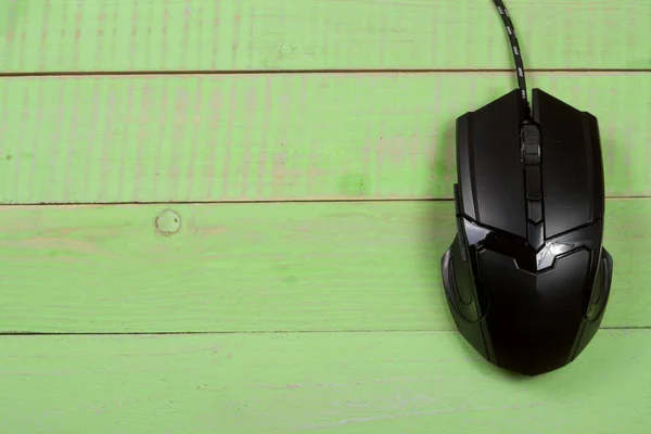 black computer mouse on a green wooden background with copy space for your text. Top view