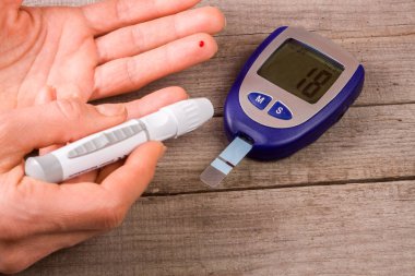 eski bir ahşap zemin üzerinde bir el ile kan şekeri ölçüm cihazı