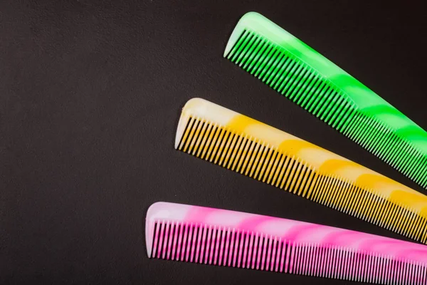 Three different colored hairbrushes on a dark background — Stock Photo, Image