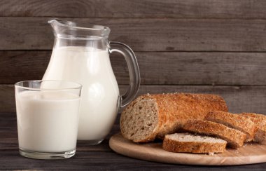 sürahi ve bardak süt bir somun ekmek ahşap zemin ile