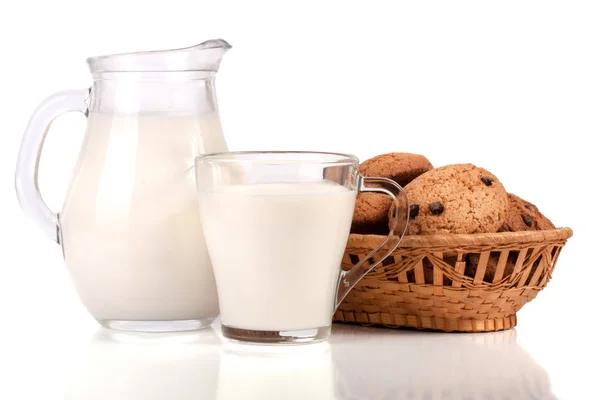 Jarro e copo de leite com biscoitos de aveia em uma cesta de vime isolada em fundo branco — Fotografia de Stock