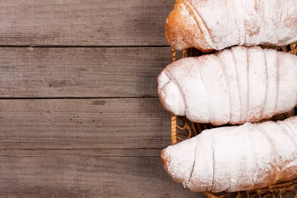 Croissants polvilhados com açúcar em pó no fundo de madeira velho com espaço de cópia para o seu texto. Vista superior — Fotografia de Stock