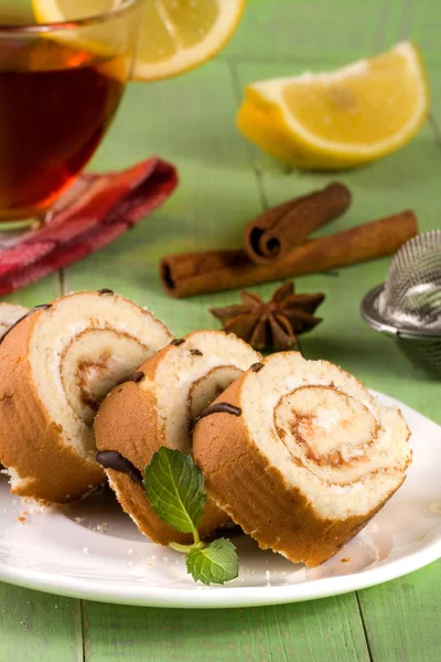 Keksrolle mit einer Tasse Tee auf grünem Holzhintergrund — Stockfoto