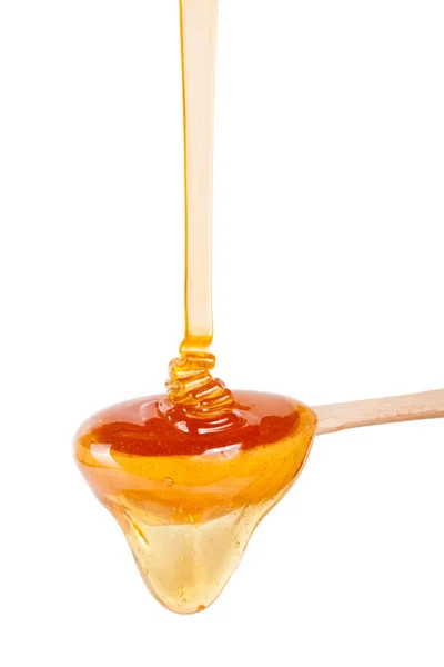 Μέλι με ένα ξύλινο κουτάλι απομονωθεί σε λευκό φόντο — Φωτογραφία Αρχείου