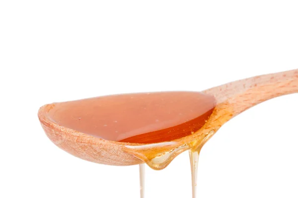 Honig in einem Holzlöffel isoliert auf weißem Hintergrund — Stockfoto