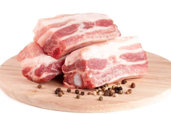 Trozos de cerdo con pimienta en una tabla de cortar aislada sobre fondo blanco — Foto de Stock