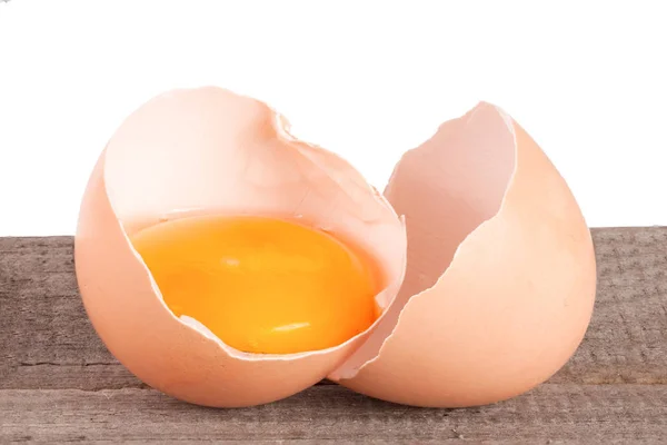 Uovo rotto con tuorlo e guscio d'uovo su un tavolo di legno con sfondo bianco — Foto Stock