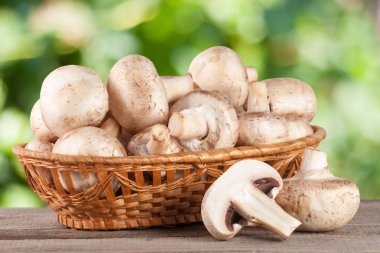 Bulanık Bahçe arka plan ile ahşap masa üzerinde bir hasır sepet champignon mantar