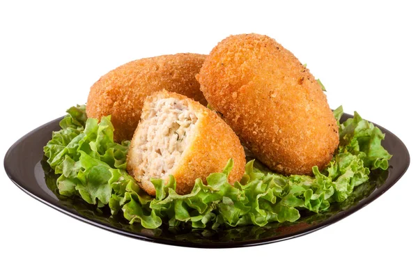 Three fried breaded cutlet with lettuce on a black plate isolated white background — Stock Photo, Image