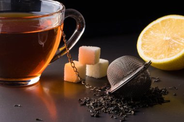 bir süzgeç ve koyu arka plan üzerinde limon ile çay