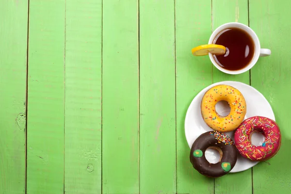 一杯茶绿色木背景与副本空间为您的文本上的甜甜圈。顶视图 — 图库照片