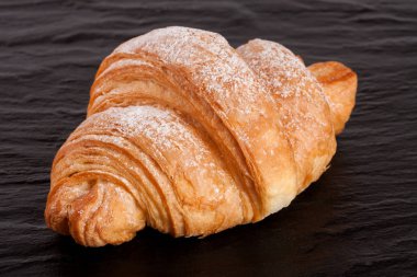 siyah taş arka plan üzerinde bir kruvasan