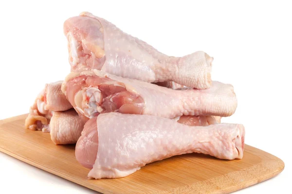 Palillos de pollo crudos sobre un fondo blanco de corte de madera — Foto de Stock