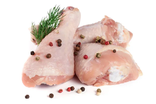 Three raw chicken drumsticks with a sprig of dill and peppercorns isolated on white background Stock Image