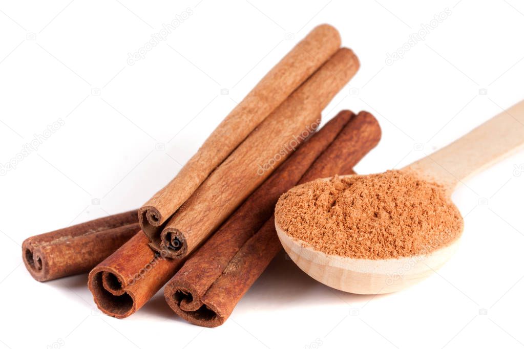 four cinnamon sticks and powder with spoon isolated on white background