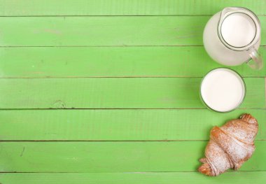 sürahi ve bardak süt kopya alanı metniniz için yeşil bir ahşap zemin üzerine kruvasan ile. Üstten Görünüm