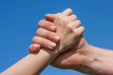 Bir çocuk ve yetişkin mavi gökyüzü karşı el sıkışma