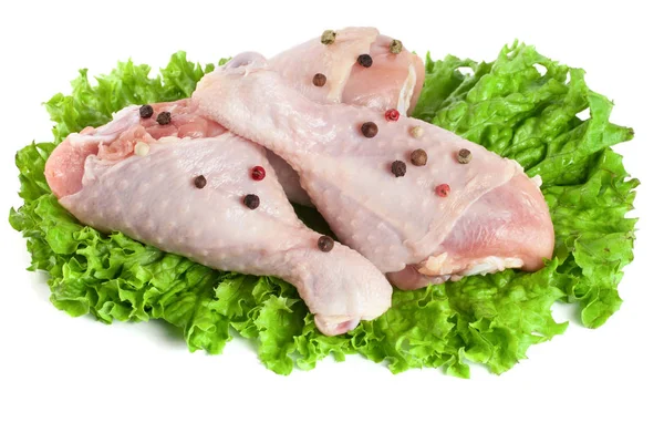 Three raw chicken drumsticks with lettuce leaf isolated on white background Stock Photo