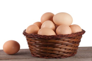 Beyaz bir arka plan üzerinde ahşap bir gemide bir hasır sepet yumurta