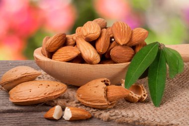 soyulmuş badem ile bir tahta kaşık masada yaprak yığını Bahçe arka plan bulanık