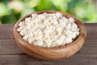 Bahçe arka plan bulanık gemide ahşap bir kase süzme peynir