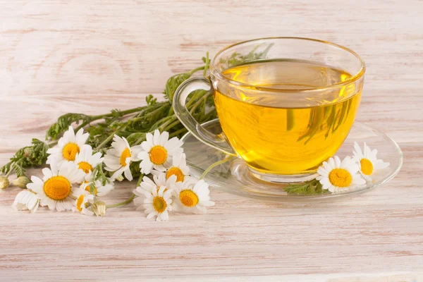 Hafif ahşap arka plan üzerinde taze papatya çiçeği ile bitkisel çay