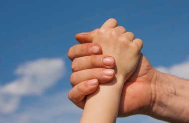 Bir çocuk ve yetişkin mavi gökyüzü karşı el sıkışma