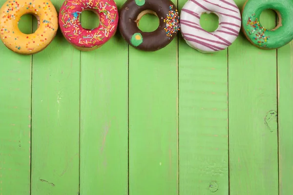 glazed donuts on a green wooden background with copy space for your text. Top view