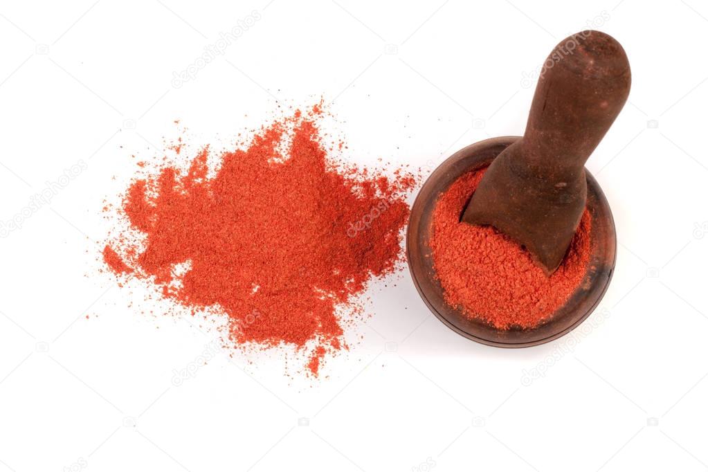 Paprika powder in a wooden bowl with a scoop isolated on white background. Top view