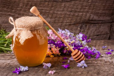 Kavanoz bal ile eski ahşap arka plan üzerinde kır çiçekleri