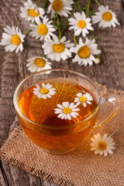 Eski ahşap zemin üzerine taze papatya çiçeği ile bitkisel çay