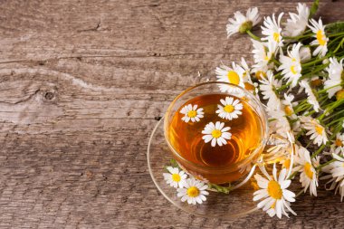 Kopya alanı metniniz için eski ahşap zemin üzerine taze papatya çiçeği ile bitkisel çay