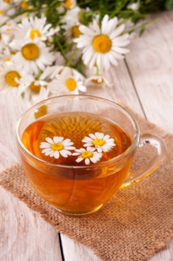 Beyaz ahşap zemin üzerinde taze papatya çiçeği ile bitkisel çay