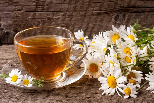 Eski ahşap zemin üzerine taze papatya çiçeği ile bitkisel çay