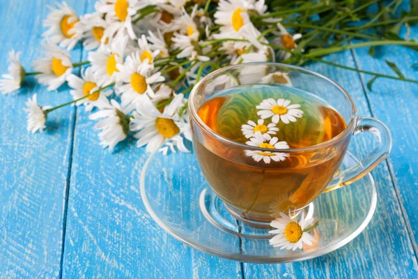 Mavi ahşap zemin üzerine taze papatya çiçeği ile bitkisel çay