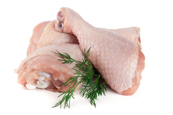 Three raw chicken drumsticks with a sprig of dill isolated on white background