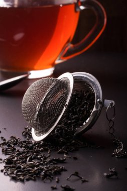 çay süzgeci ile bir fincan koyu arka plan üzerinde