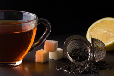 bir süzgeç ve koyu arka plan üzerinde limon ile çay