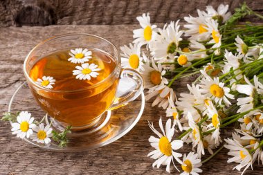 Eski ahşap zemin üzerine taze papatya çiçeği ile bitkisel çay