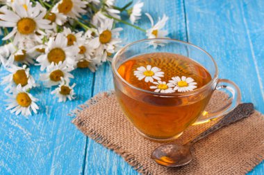 Mavi ahşap zemin üzerine taze papatya çiçeği ile bitkisel çay