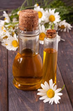 esans ve koyu ahşap arka plan üzerinde taze papatya çiçeği ile şişe