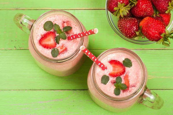 Verre de yaourt aux fraises ou smoothie aux feuilles de menthe sur fond de bois vert. Vue du dessus — Photo