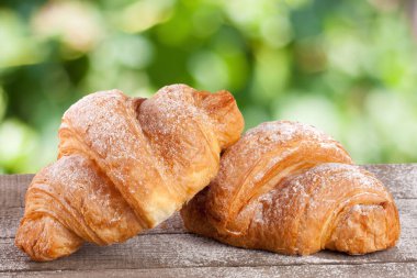 iki ay çöreği bulanık bir bahçe arka plan ile ahşap bir gemide pudra şekeri serpilir