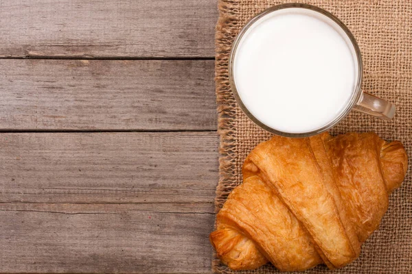 Pohár tej, croissant-t, a régi fa háttér, a szöveg másolása szóközzel. Szemközti nézet — Stock Fotó