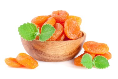 Nane yaprakları üzerinde WHI izole bir ahşap kase kuru kayısı